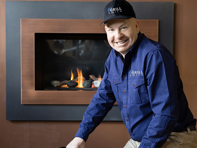 A professional contractor man smiling in front of modern fireplace installed on the wall